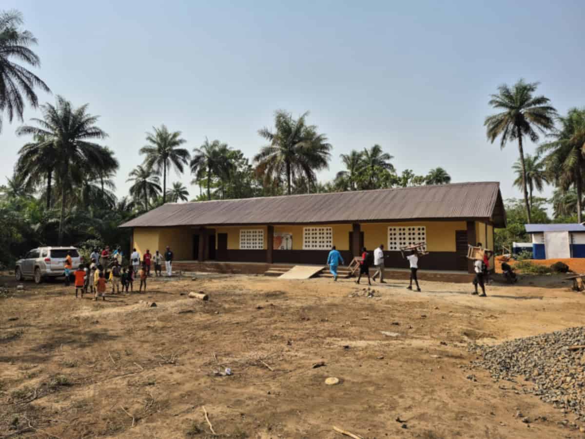 Schoolgebouw met palmbomen en kinderen in een ontwikkelingsland.